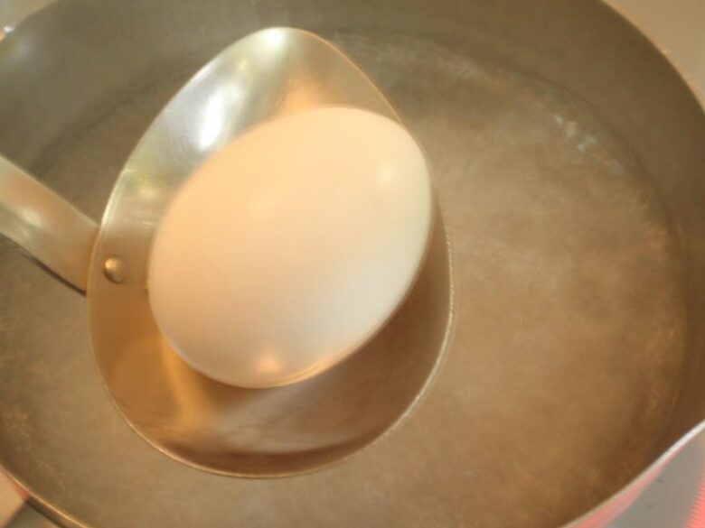 ゆで卵の作り方　卵をお玉に載せて、一個ずつ沸騰したお湯に入れる