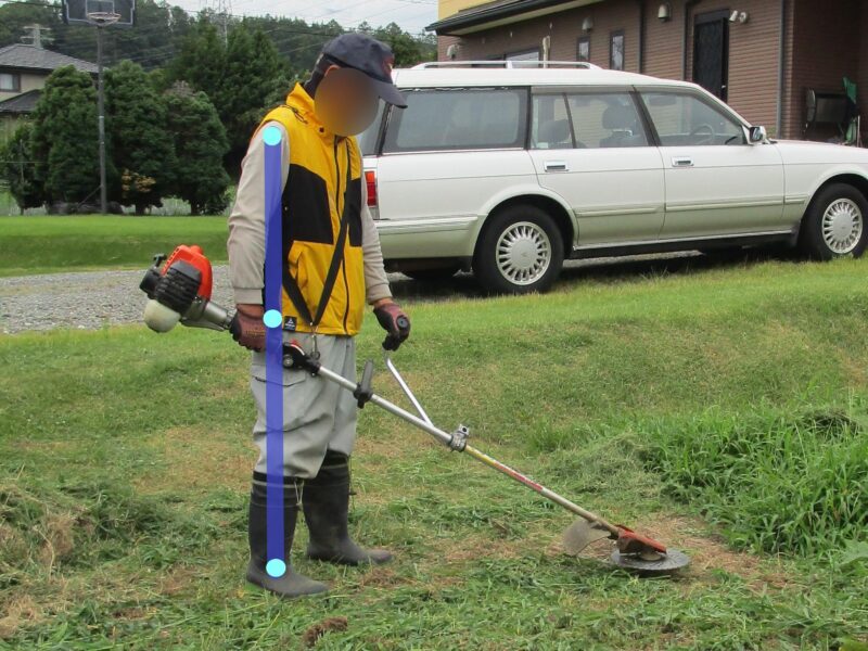 ループハンドルの刈払機（草刈り機）での草刈り作業で腰を曲げずに作業する案⓷市販の補助ハンドルを取り付けて草刈りをしている姿勢の説明写真　背筋はほぼ真っ直ぐで、腰に負担がかかりません。