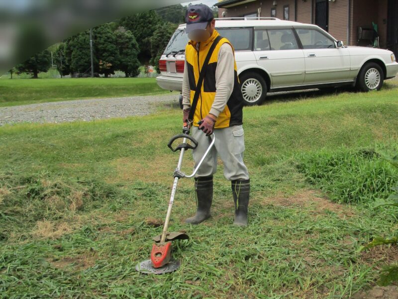 ループハンドルの刈払機（草刈り機）での草刈り作業で腰を曲げずに作業する案⓷市販の補助ハンドルを取り付けて草刈りをしている姿勢の説明写真