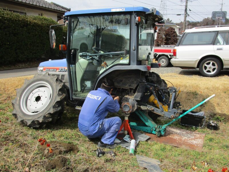 イセキの販売業者が動深耕センサーの交換作業を行っており、タイヤを外して修理している。