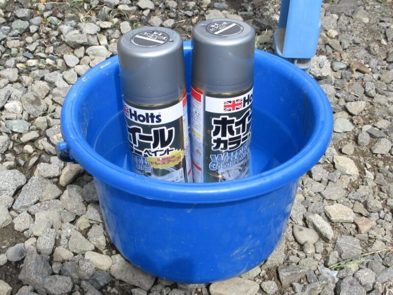 塗装をきれいにするためにスプレー缶をバケツで湯煎する様子