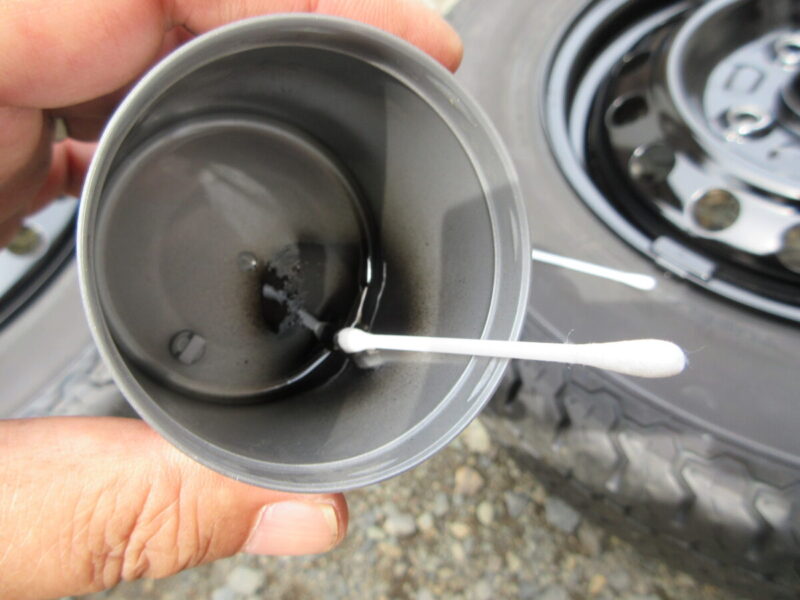 スプレー缶の蓋に溜めた塗料を綿棒につけてホイールの塗り残しを補修する様子