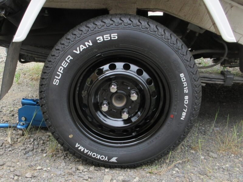 ハイゼットトラックの黒塗装純正ホイールに、普通車（クラウンステーションワゴン）用の社外品の長いメッキナットを装着した状態。