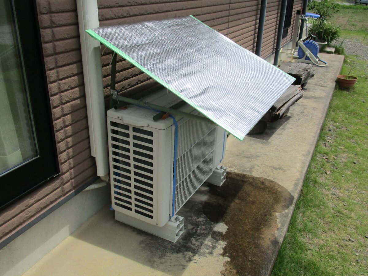 DIYで自作したエアコン室外機の日よけ（カバー）。アルミシートと園芸支柱を使い、室外機全体を日陰にして省エネ効果を高めている様子。